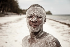 A boy covered in sand on Bamburi beach, Mombasa, Kenya